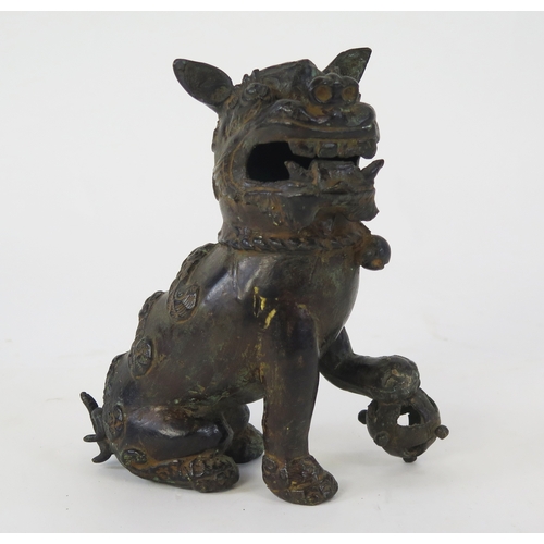 1101 - A Chinese bronze censer modeled as a Buddhistic lion, with one paw resting on a pierced globe, 20cm ... 