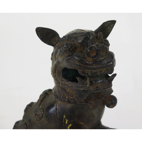 1101 - A Chinese bronze censer modeled as a Buddhistic lion, with one paw resting on a pierced globe, 20cm ... 