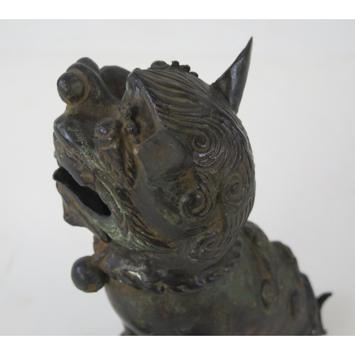 1101 - A Chinese bronze censer modeled as a Buddhistic lion, with one paw resting on a pierced globe, 20cm ... 