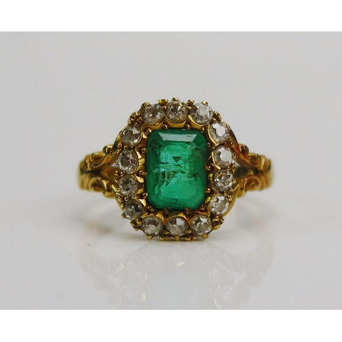 64 - An Edwardian 18ct yellow gold, emerald and diamond cluster ring with scrolled openwork shoulders c. ...