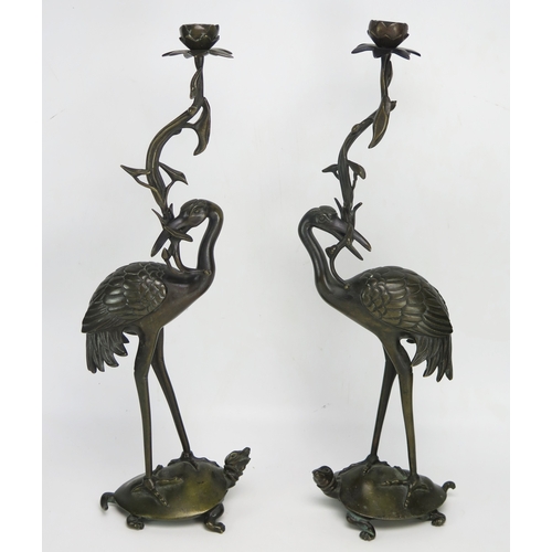 1101A - A pair of Chinese bronze candlesticks , the foliate branch held in the beak of a crane standing on a... 