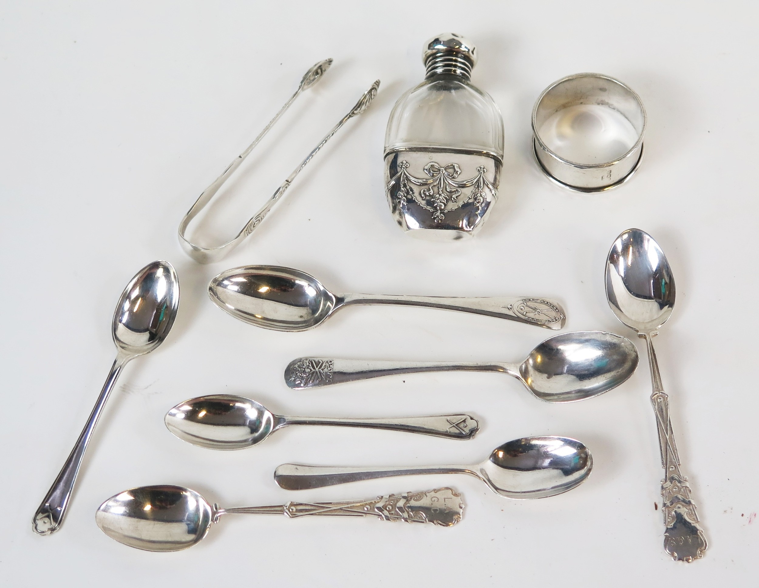 A mixed collection of silver flatwares, napkin ring, sugar tongs, hip ...