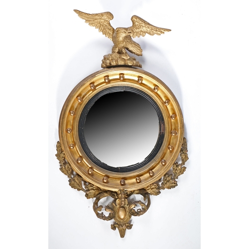 23 - A Regency giltwood convex wall mirror, the circular mirror plate housed in an ebonised slip, the mou... 