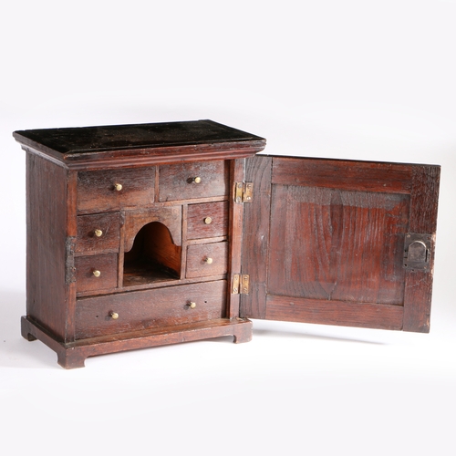 277 - An early 18th century table-top oak spice cupboard, circa 1710-30

 Having a fielded panelled cupboa... 