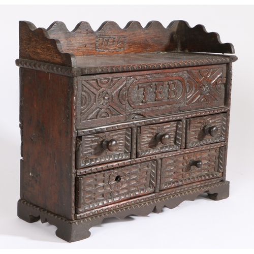 364 - An early 18th century oak spice cabinet, dated 1714

 Having a hinged top and carved frieze initiall... 