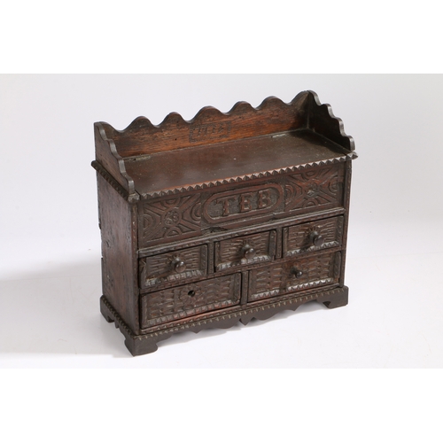 364 - An early 18th century oak spice cabinet, dated 1714

 Having a hinged top and carved frieze initiall... 