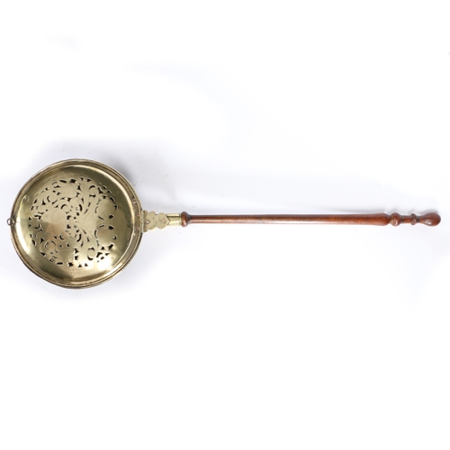 444 - An 18th century brass and fruitwood warming pan, Dutch

 The pan with domed lid, pierced and engrave... 