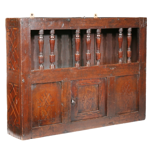 652 - A Charles II oak and inlaid mural spindle livery cupboard, circa 1660

 Having a row of seven turned... 