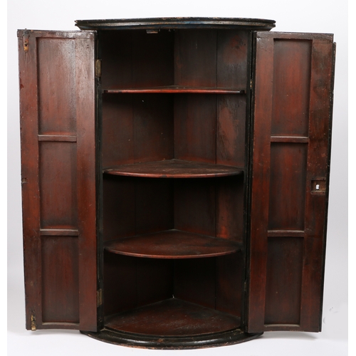 656 - A George III pine painted mural corner cupboard, circa 1800

 Of bow-front form, the doors painted w... 