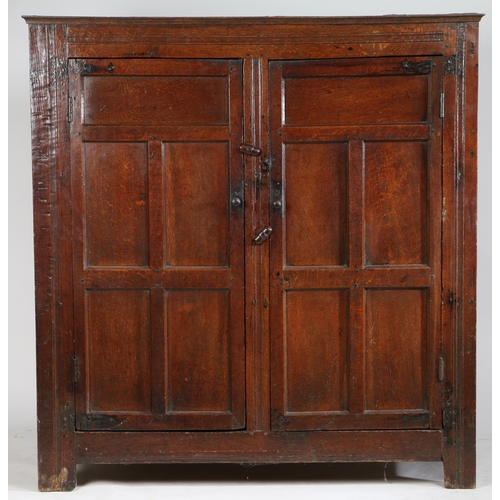 308 - A late 17th Century oak livery cupboard

 Having a pair of five-panelled cupboard doors, on extended... 