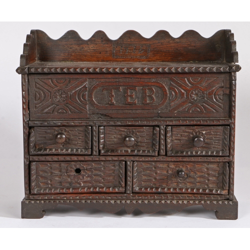 364 - An early 18th century oak spice cabinet, dated 1714

 Having a hinged top and carved frieze initiall... 