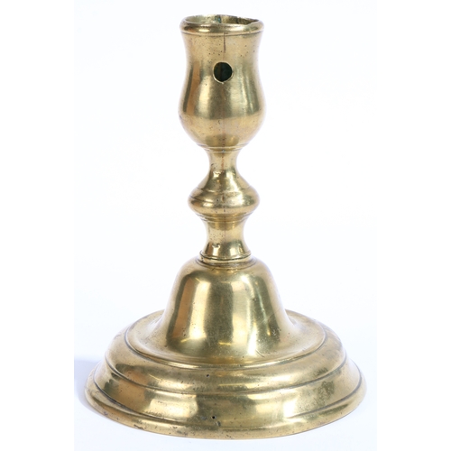 411 - An early 18th century brass candlestick, Dutch, circa 1720

 Having a tulip-shaped socket, with circ... 