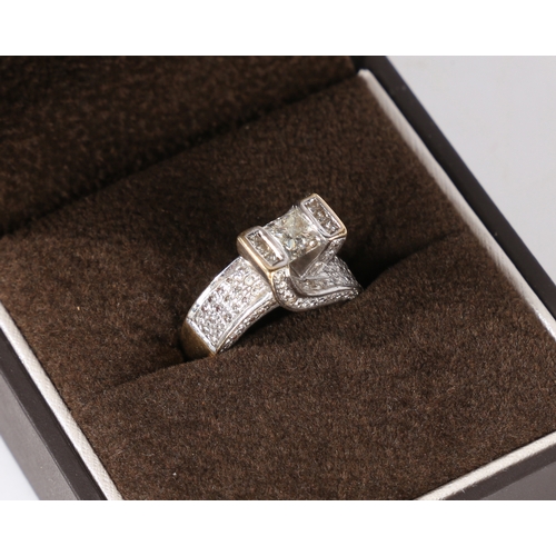 21 - An 18 carat gold and diamond ring, the head set with a central princess cut diamond estimated at 0.9... 