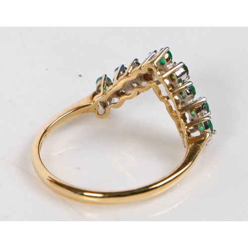 67 - An 18 carat gold, emerald and diamond ring, the V shaped head set with nine round cut emeralds and d... 