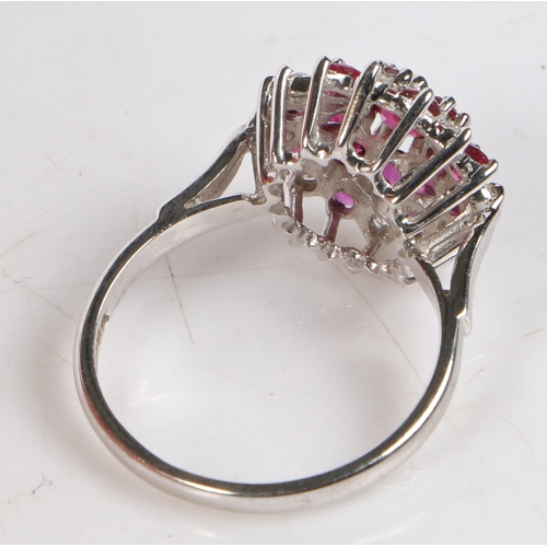 78 - An 18 carat white gold, ruby and diamond cluster ring, the central ruby surrounded by a band of rubi... 