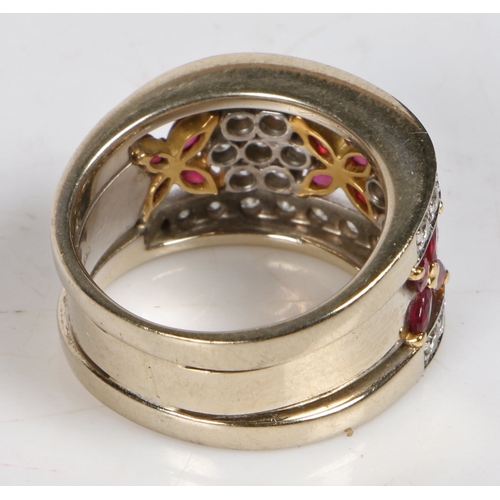 87 - An 18 carat gold, ruby and diamond ring, the pierced stylised foliate head set with twelve oval rubi... 