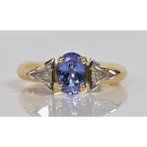 90 - An 18 carat gold, tanzanite and diamond ring, the head set with an oval tanzanite flanked by two tri... 