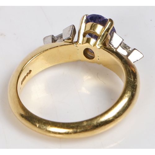 90 - An 18 carat gold, tanzanite and diamond ring, the head set with an oval tanzanite flanked by two tri... 