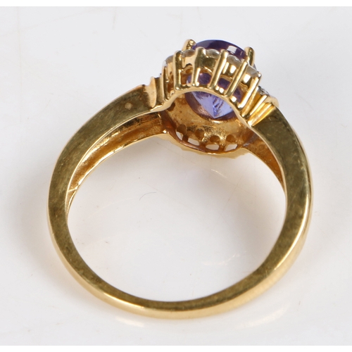 91 - An 18 carat gold tanzanite and diamond ring, the central oval facet cut tanzanite surrounded by a ba... 