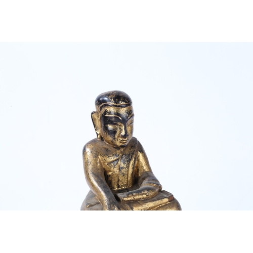 78 - A CARVED AND GILT WOOD BUDDHA. modelled in a seated position and raised on a red painted plinth base... 