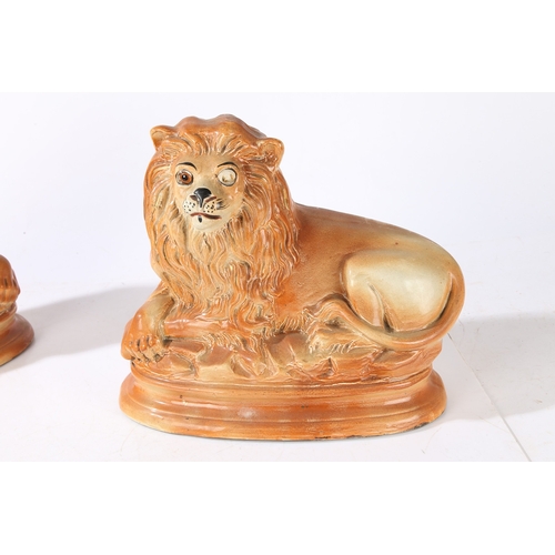 90 - A PAIR OF VICTORIAN STAFFORDSHIRE LIONS. modelled in recumbent positions with gilt highlighted manes... 