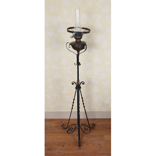 18 - A 19TH CENTURY IRON STANDARD LAMP. having scroll supports above a cylindrical column with floral mot... 