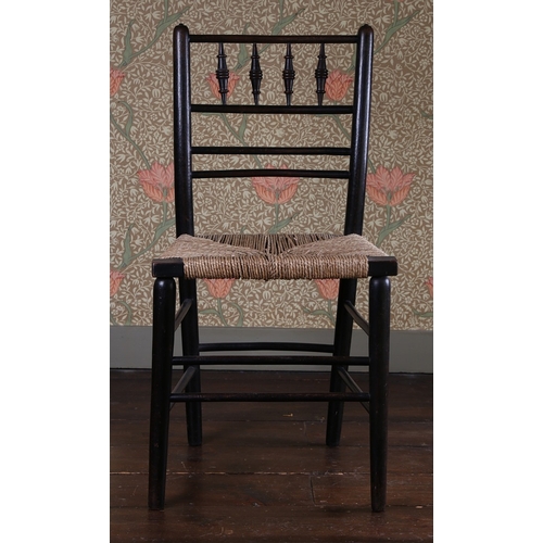 29 - A LATE 19TH CENTURY WILLIAM MORRIS EBONISED CHAIR. having a spindle back raised on a rush seat above... 