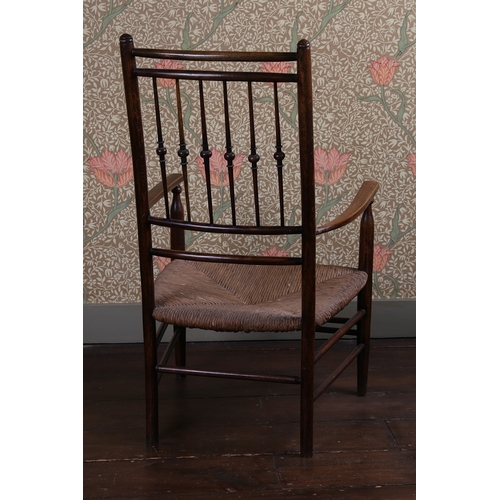 30 - A LATE 19TH CENTURY WILLIAM MORRIS ARMCHAIR. having a turned spindle back raised on rush seat having... 