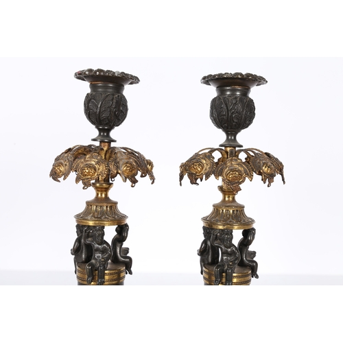 379 - A PAIR OF REGENCY STYLE STEEL AND GILT METAL CANDLESTICKS. the foliate cast sconces above pierced ha... 