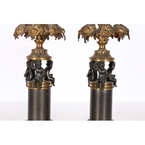 379 - A PAIR OF REGENCY STYLE STEEL AND GILT METAL CANDLESTICKS. the foliate cast sconces above pierced ha... 