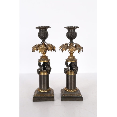 379 - A PAIR OF REGENCY STYLE STEEL AND GILT METAL CANDLESTICKS. the foliate cast sconces above pierced ha... 