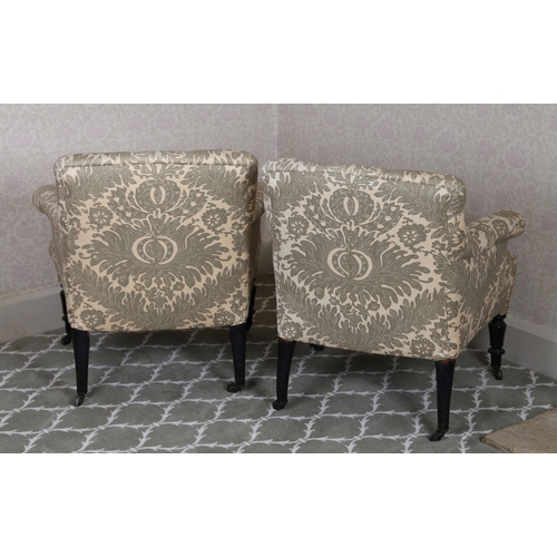 40 - A PAIR OF LATE VICTORIAN LOW ARMCHAIRS. having a buttoned back and arms raised on turned ebonised le... 