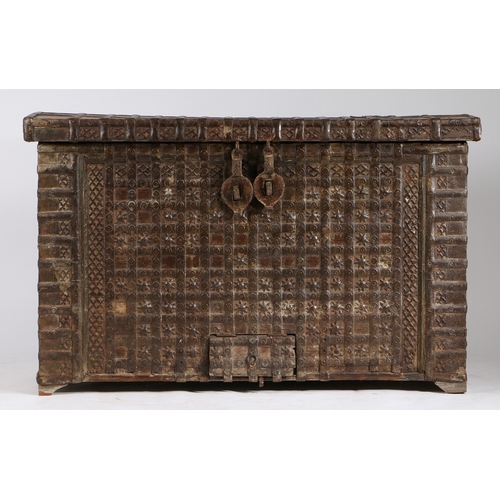 45 - AN INDIAN TEAK AND IRON BOUND CHEST. the iron banded hinged lid with two locks, the banded front wit... 