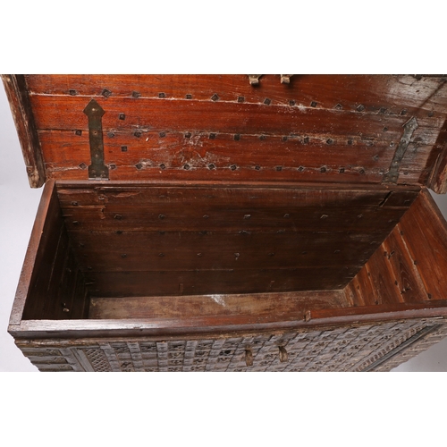 45 - AN INDIAN TEAK AND IRON BOUND CHEST. the iron banded hinged lid with two locks, the banded front wit... 