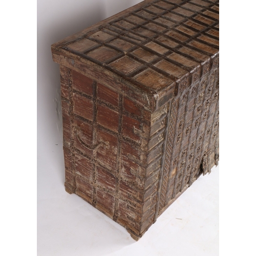 45 - AN INDIAN TEAK AND IRON BOUND CHEST. the iron banded hinged lid with two locks, the banded front wit... 