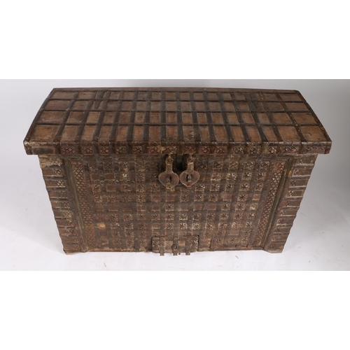 45 - AN INDIAN TEAK AND IRON BOUND CHEST. the iron banded hinged lid with two locks, the banded front wit... 