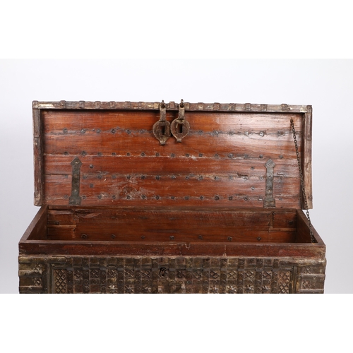 45 - AN INDIAN TEAK AND IRON BOUND CHEST. the iron banded hinged lid with two locks, the banded front wit... 