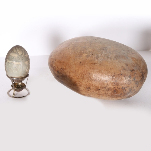 55 - A CARVED EMU EGG AND A SUBSTANTIAL SEED POD. the emu egg with depiction of a hunter and two emus, ra... 