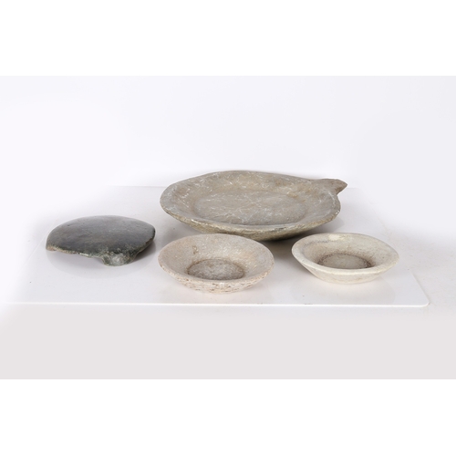 57 - AN INDIAN CHAPATI STONE, A LARGE AND TWO SMALL CARVED STONE DISHES (4). The chapati stone raised on ... 