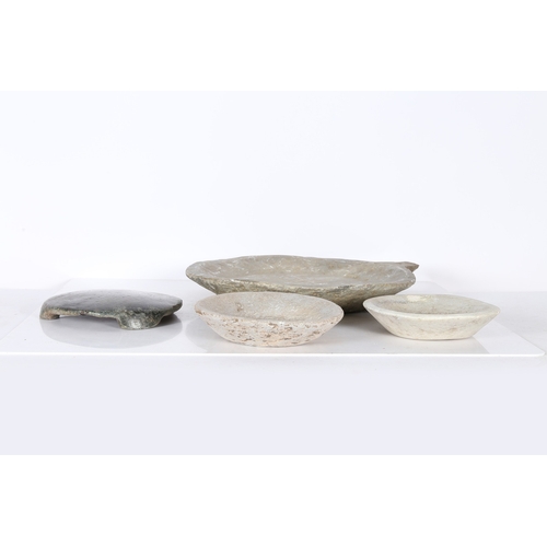 57 - AN INDIAN CHAPATI STONE, A LARGE AND TWO SMALL CARVED STONE DISHES (4). The chapati stone raised on ... 