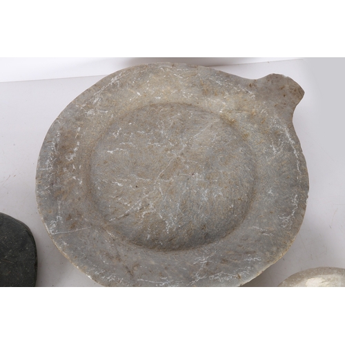 57 - AN INDIAN CHAPATI STONE, A LARGE AND TWO SMALL CARVED STONE DISHES (4). The chapati stone raised on ... 