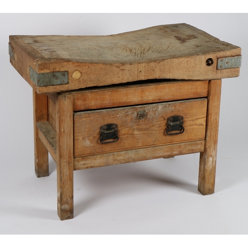 60 - A PINE BUTCHERS BLOCK. The well used block top with metal corner brackets, above a base with single ... 