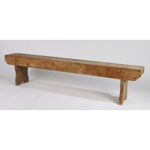 63 - A RUSTIC PINE LOW BENCH. with plank top and sides, raised on silhouette end supports, 152.5cm wide, ... 