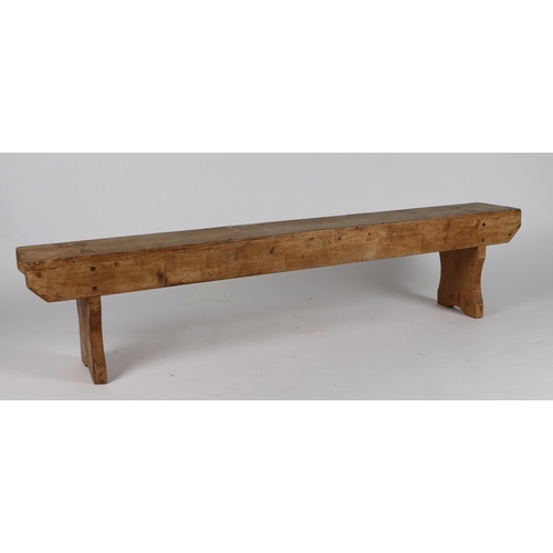 63 - A RUSTIC PINE LOW BENCH. with plank top and sides, raised on silhouette end supports, 152.5cm wide, ... 