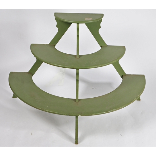 69 - A DEMI-LUNE THREE TIER PLANT STAND. with three graduated green painted shelves on silhouette support... 