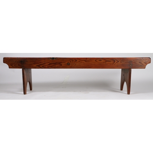 73 - A RUSTIC PINE LOW BENCH. with plank top and sides, raised on silhouette end supports, 161.5cm wide, ... 