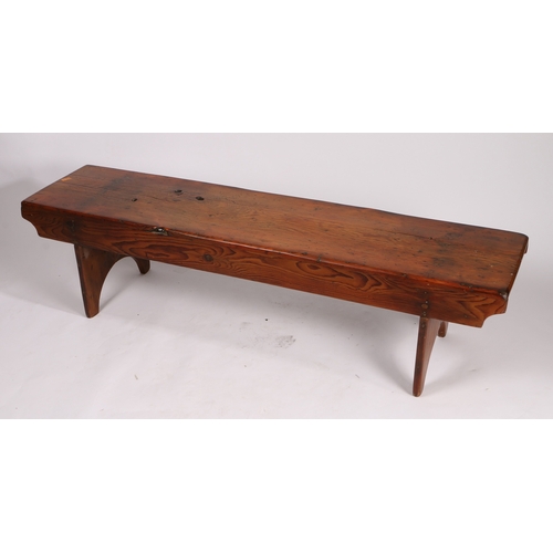 73 - A RUSTIC PINE LOW BENCH. with plank top and sides, raised on silhouette end supports, 161.5cm wide, ... 