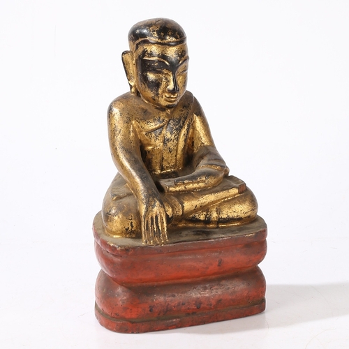 78 - A CARVED AND GILT WOOD BUDDHA. modelled in a seated position and raised on a red painted plinth base... 