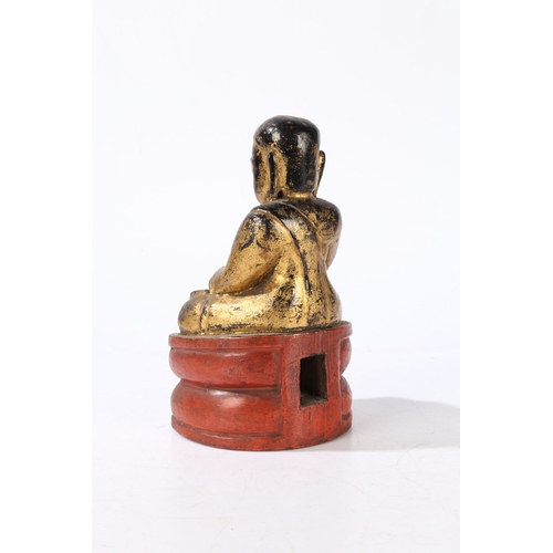 78 - A CARVED AND GILT WOOD BUDDHA. modelled in a seated position and raised on a red painted plinth base... 