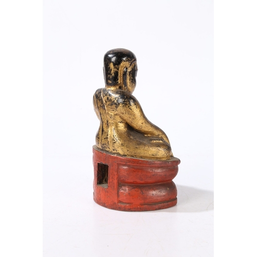 78 - A CARVED AND GILT WOOD BUDDHA. modelled in a seated position and raised on a red painted plinth base... 